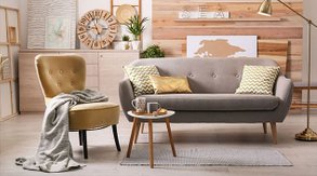 Omklädda möbler i ett vardagsrum, en fåtölj i gul sammet och en soffa i beige möbeltyg. 