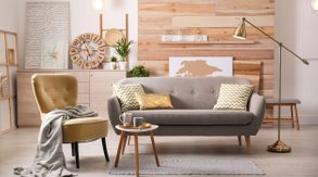Omklädda möbler i ett vardagsrum, en fåtölj i gul sammet och en soffa i beige möbeltyg. 